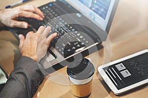 Close up cup of coffee on table. Businessman hands typing on his