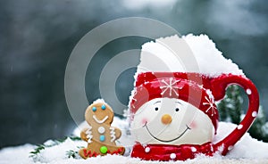 Close-up of cup with snowman face full of snow and gingerbread