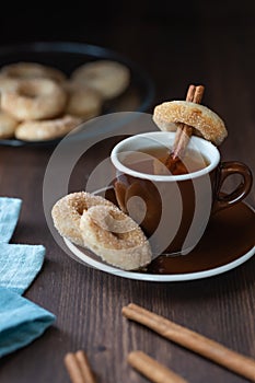 Close up of a cup of tea served with mini sugar and cinnamon donuts.