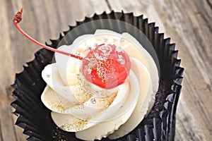 Close up of a cupcake with a red glased cherry