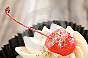 Close up of a cupcake with a red glased cherry