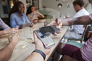 Close Up Of Customer In Restaurant Paying Bill With Contactless Phone App