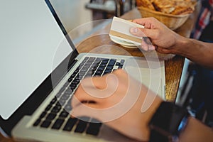 Close-up of customer spending money on online at cafe