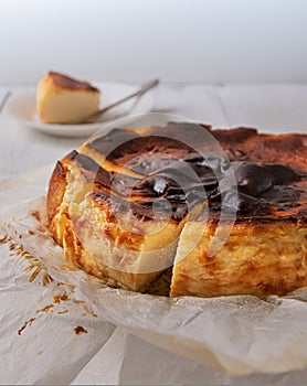 Close-up of cut basque burnt cheesecake in baking paper on wooden table