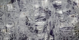 Close-up of cut and cisiliated colourless drinking glasses with abstract patterns