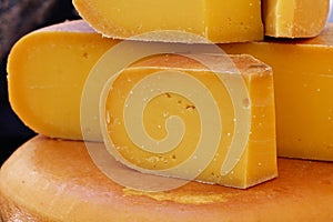 Close up cut slices and wheel of hard gouda cheese