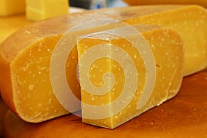 Close up cut slices and wheel of hard gouda cheese