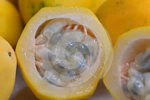 Close-up of cut yellow golden passion fruit with its distinctive rind and numerous tiny, dark brown or black, pitted seeds