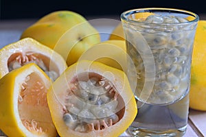 Close-up of cut yellow golden passion fruit with its distinctive rind and numerous tiny pitted seeds in a shot glass
