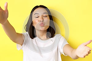 Close up of cute asian woman stretch out hands to hold smartphone camera, pucker lips and taking selfie with kissing