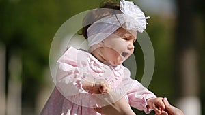 Close-up of the cute baby-girl playing and dancing in the park.