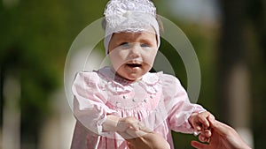 Close-up of the cute baby-girl playing and dancing in the park.