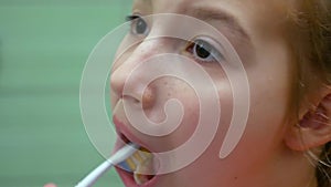 Close-up cute beautiful female child with fair hair brushes her teeth thoroughly and smiles