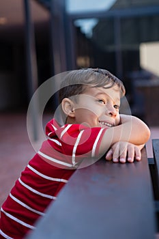 Close up of cute boy looking away while leaning on table