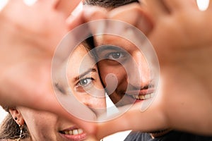 Close-up of cute couple through heart symbol made with fingers