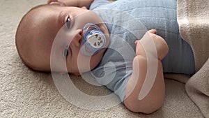 Close-up Cute Funny Kid 2 Month Newborn Boy With Pacifier Looking At Camera After Bath Shower On White Soft Bed. Baby