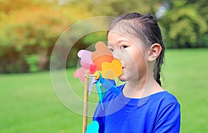 Close up cute little Asian child girl with wind turbine in the garden