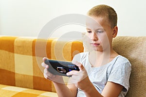 Close-up of cute little boy using smartphone looking at screen, curious child