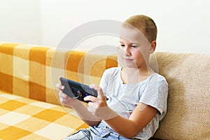 Close-up of cute little boy using smartphone looking at screen, curious child