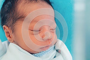 close up of cute little newborn asian baby boy 1 day sleeping on blue bed at the hospital with copy space. new family, healthy,