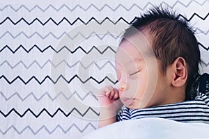 Close up of cute little newborn asian baby boy sleeping on bed at children bedroom with copy space. family, healthy, life and
