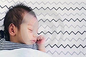 Close up of cute little newborn asian baby boy sleeping on bed at children bedroom with copy space. family, healthy, life and