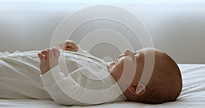 Close up cute newborn baby in bodysuit lying on bed