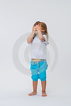 Close-up of a cute pretty little girl standing with her hands covered her face, isolated on white background