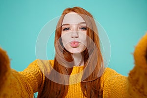 Close up of cute redhead girl in yellow sweater isolated on blue turquoise background. People lifestyle concept. Mock up