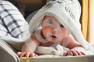 Close-up of a cute white Caucasian baby on a changer wrapped in a towel looking at the camera