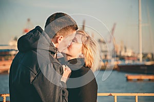 Close up of a cute young beautiful couple at pier at sunset, man kissing his girlfriend softly, hipster, happy smiling
