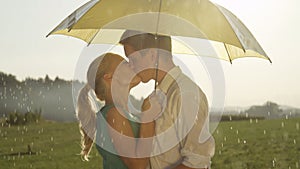 CLOSE UP: Cute young couple smiles and kisses in the refreshing summer rain.