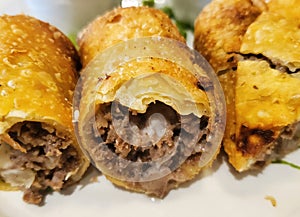 Close up of the cuts of cheesesteak rolls on a white plate