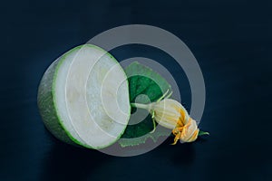 Close up of cutted zucchini, green leaf and yellow flower on black background. Summer squash