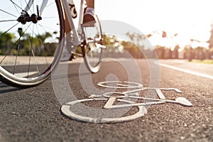 Close up cycling logo image on road with athletic women cyclist legs riding Mountain Bike in background at the morning