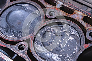 Close-up of a damaged piston of an internal combustion engine with carbon deposits in the cylinder block of a faulty