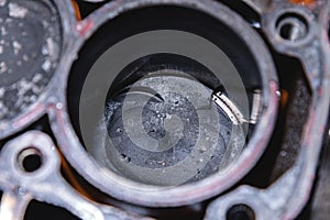 Close-up of a damaged piston of an internal combustion engine with carbon deposits in the cylinder block of a faulty