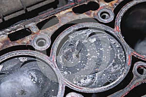 Close-up of a damaged piston of an internal combustion engine with carbon deposits in the cylinder block of a faulty