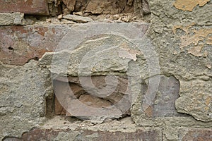 Close up of damaged wall revealing old bricks and grey plaster