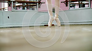 close up, in dancing hall, ballerina perform ssissonne simples , She is standing on toes in pointe shoes elegantly , on photo