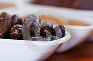 Close up of a dark dry cocoa bean inside of a white bowl