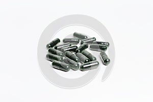 Close-up of dark green capsule pills isolated on white background.