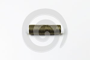 Close-up of dark green thread spool isolated on white background.