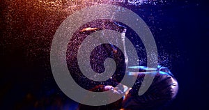 Close-up of a dark-haired middle-aged woman doing a somersault in a Studio under water and floating on a dark background