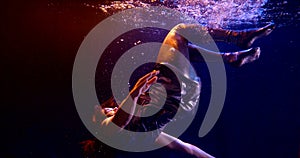 Close-up of a dark-haired middle-aged woman falling in a Studio under water and floating on a dark background, she is