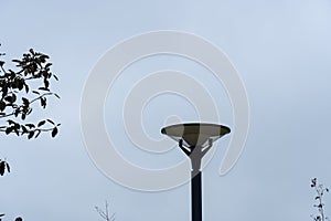 Close up of dark LED lamppost towards Grey sky and trees branches. Reidi tee, Tallinn, Estonia