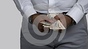 Close up dark skinned hands with money locked in handcuffs.