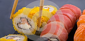 Close-up, on a dark table, assorted Japanese rolls, with tuna, salmon and tempura