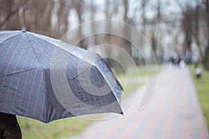 Close-up of dark umbrella during rain.