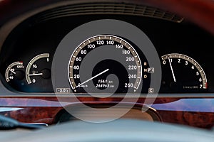 Close-up of a dashboard with elements of a tree in a car`s design with a tachometer and speedometer indicating fuel level and